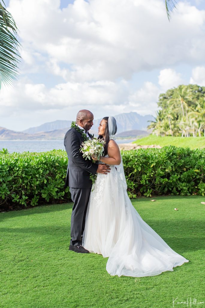 bride and groom embracing with hawaii mountains in background 