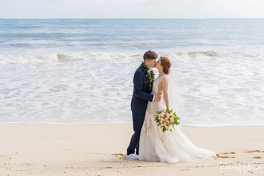 couple kiss after just married on oahu beach 