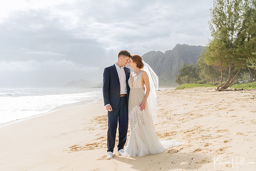 bride and groom pose on waimanalo beach during morning wedding 