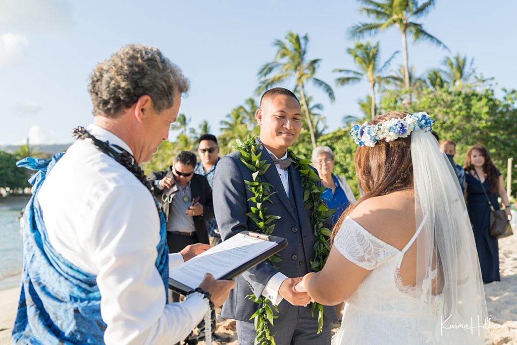 candid beach wedding photo of groom looking at bride 
