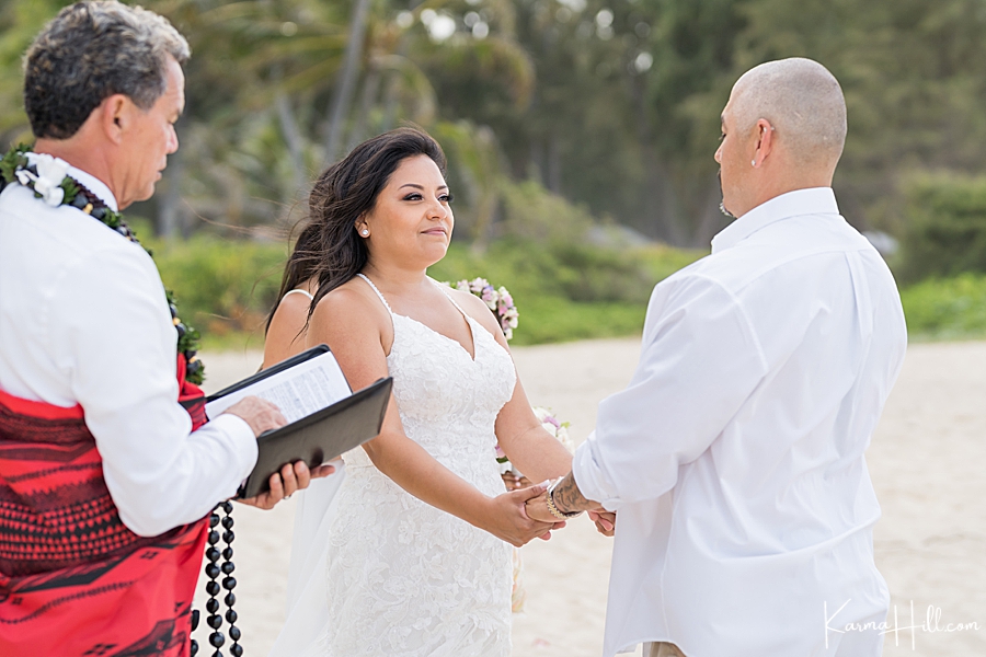 bride and groom hold hands as hawaiian reverend officiates 