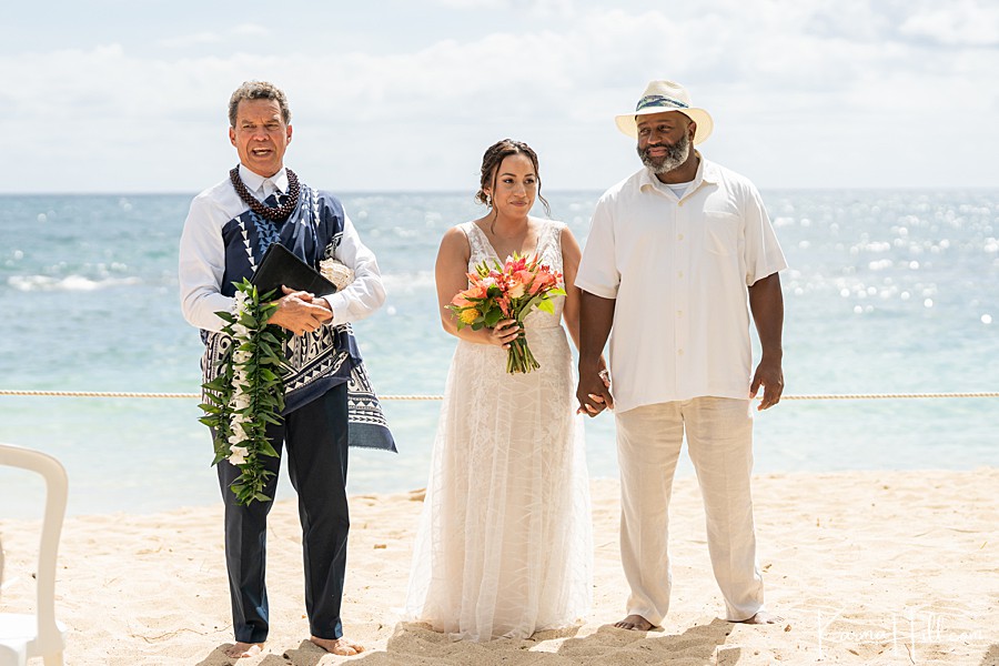 couple hold hands as they're married on oahu beach 