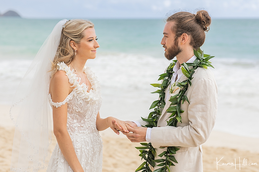 groom gives bride ring at beach wedding