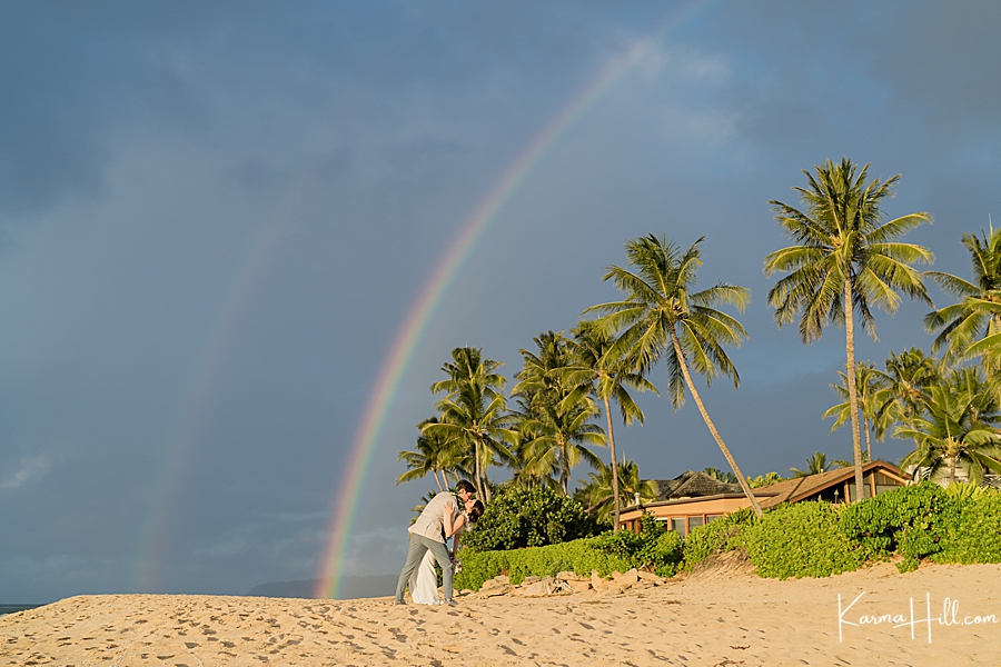 bride and groom kiss under rainbow